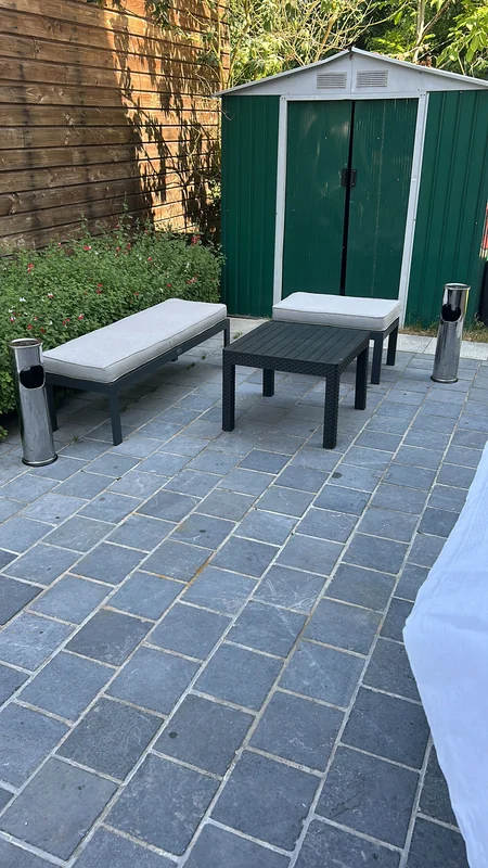 Banc de jardin contre le mur en pierre avec cabanon vert
