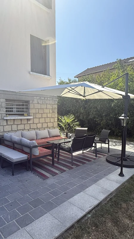 Terrasse avec salon de jardin et grand parasol déporté ouvert