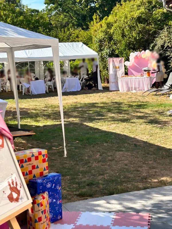 Vue d'ensemble du jardin avec chapiteaux, tables dressées et décoration d'anniversaire rose