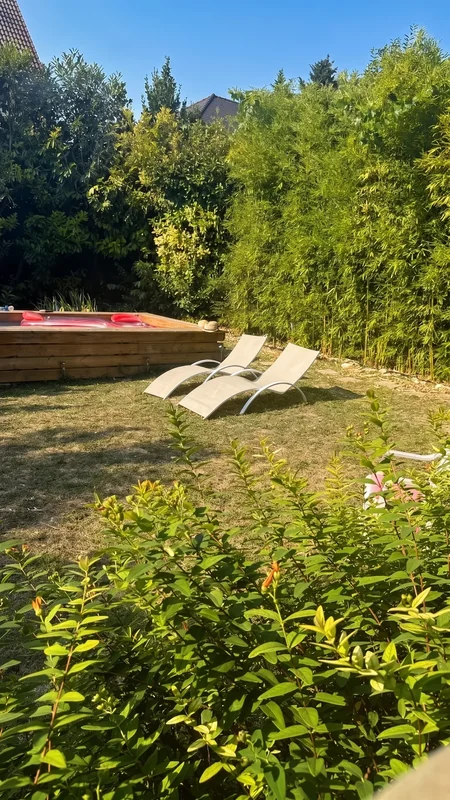 Transats blancs sur la pelouse face à la piscine du jardin de Sarcelles