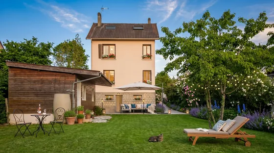 Vue d'ensemble sur la maison, la pelouse, le salon de jardin et un transat au crépuscule