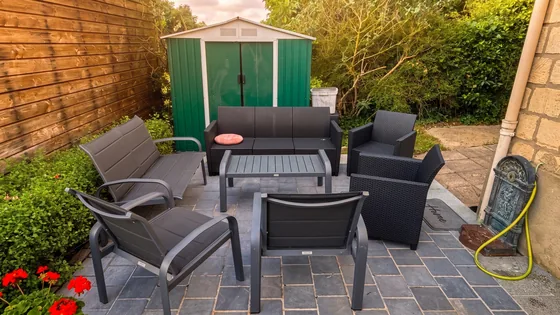 Salon de jardin avec chaises et canapé sur la terrasse carrelée par beau temps
