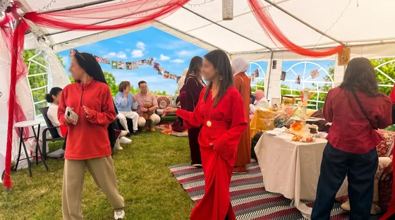 Fête sous chapiteau avec invités en tenues colorées, décoration festive et table de buffet