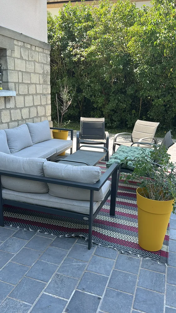 Terrasse avec salon de jardin, canapé gris et tapis d'extérieur