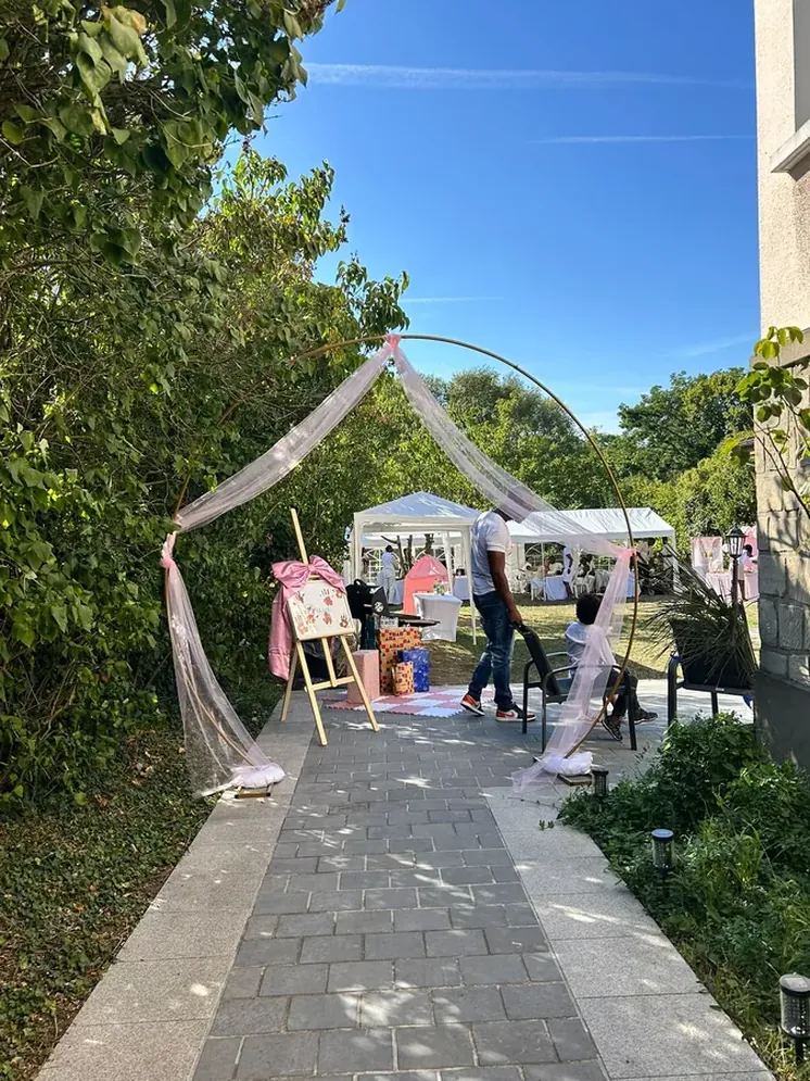 Arche florale rose à l'entrée du jardin avec chapiteaux blancs pour un anniversaire