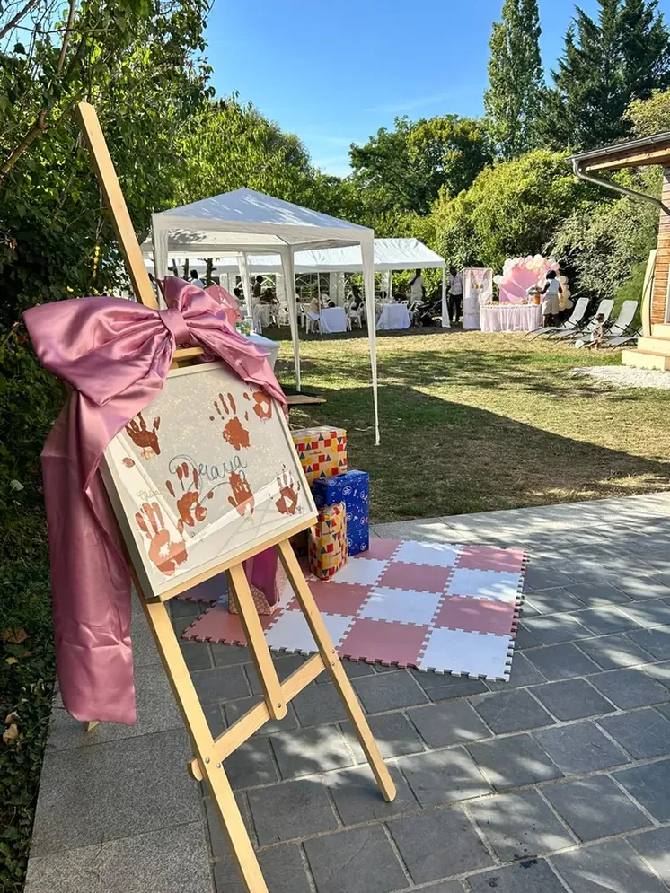 Chevalet avec cadre à empreintes de mains et cadeaux sur tapis de sol dans le jardin