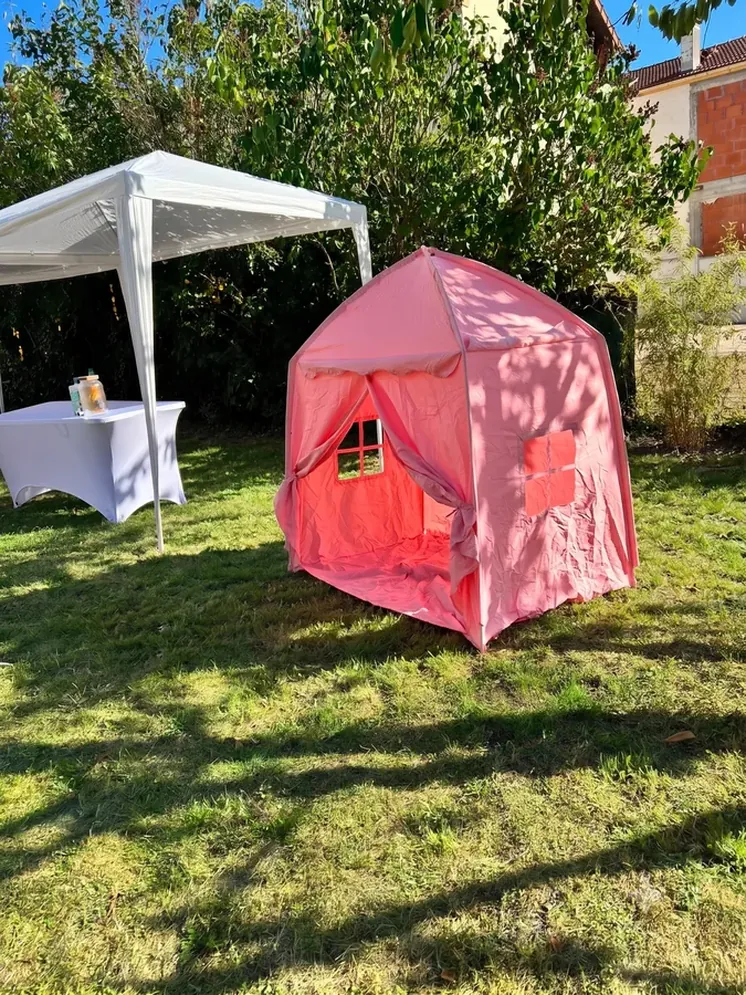 Tente enfant rose installée dans le jardin près du chapiteau