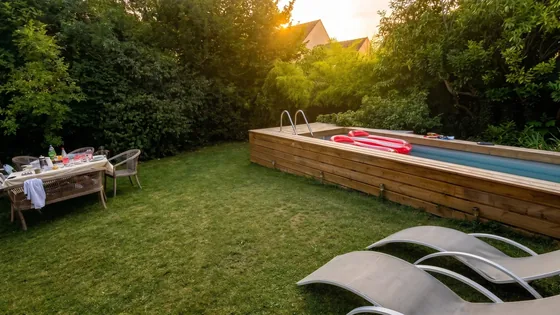 Table dressée et transats face à la piscine du jardin de Sarcelles au coucher du soleil
