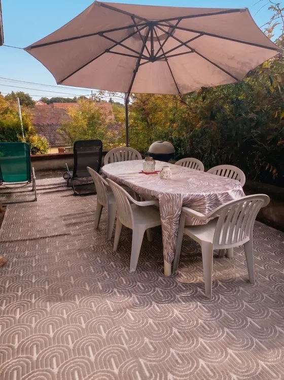 Terrasse avec grande table, chaises et parasol dans le jardin de Sarcelles