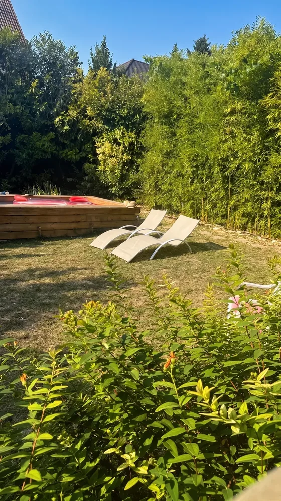 Transats blancs sur la pelouse face à la piscine du jardin de Sarcelles