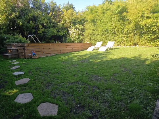 Piscine en bois surélevée et transats sur la pelouse bordée de bambous à Sarcelles