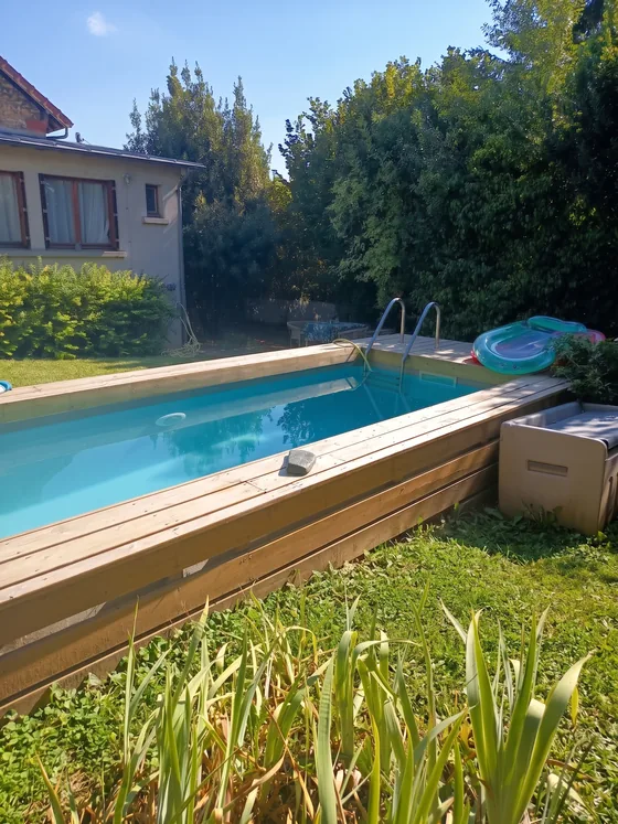 Piscine en bois avec échelle et bouées face à la maison du jardin de Sarcelles